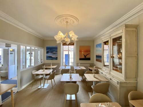Élégante salle à manger de l'Hôtel Maison Richet avec œuvres côtières, lustre moderne et mobilier beige dominant Les