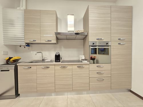 Moderna kuhinja od svijetlog drva u Raymihome Torino apartmanu sa uređajima od nehrđajućeg čelika i blagovaonom zonom