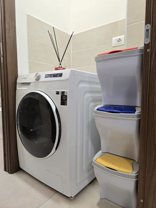 Praonica apartmana Raymihome u Torinu s bijelom Samsung perilicama i naslaganim spremnicama za pohranu