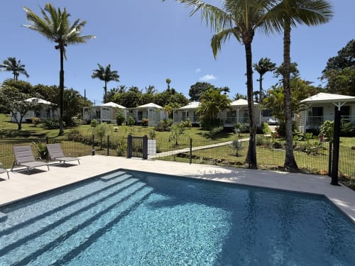 Piscine avec transats au Domaine de la Glacière à Petit Bourg, entourée de palmiers et bungalows