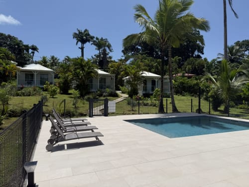 Zone de la piscine du Domaine de la Glacière à Petit Bourg avec chaises longues, bungalows et jardins tropicaux sous ciel dégagé