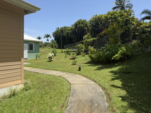 Allée du jardin du Domaine de la Glacière avec plantes tropicales et bungalow à Petit-Bourg, Guadeloupe