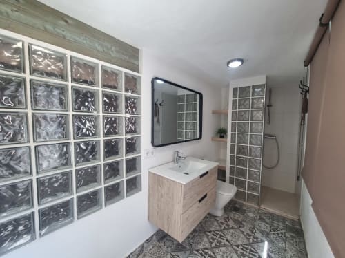 Baño moderno en Penthouse Gracia de CTH Granada con paredes de ducha de bloques de vidrio, tocador de madera y espejo
