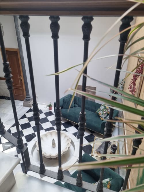 Elegante interior de ático Gracia con barandillas ornamentales negras, suelo de cuadros, sofá verde y planta en maceta en CTH