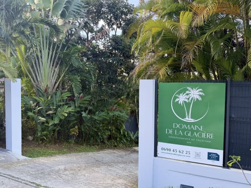 Panneau d'entrée du Domaine de la Glacière avec végétation tropicale à Petit-Bourg, Guadeloupe