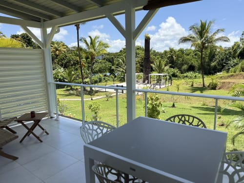 Terrasse couverte du Domaine de la Glacière avec tables, jardins tropicaux et palmiers à Petit-Bourg, Guadeloupe