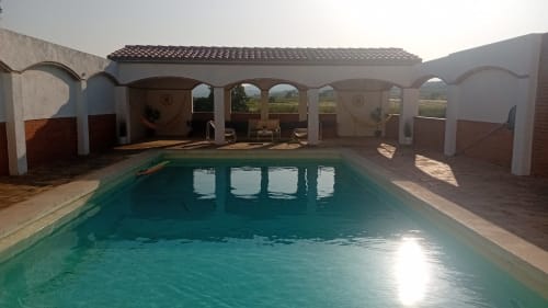 Terraza piscina cubierta en Masía Rural Ca l'Eloi Janet cerca de Barcelona con agua turquesa y columnas arqueadas