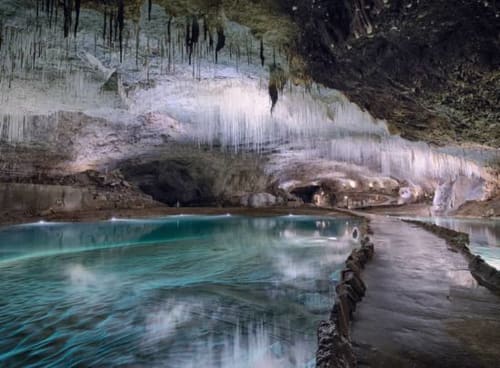 Turquoise geothermal pool beneath icy cave formations at Maison de Sophie, Rencurel, FR