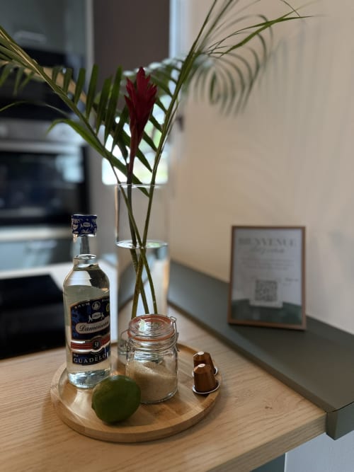 Bouteille de rhum et fleurs fraîches sur plateau en bois au Domaine de la Glacière, Petit-Bourg