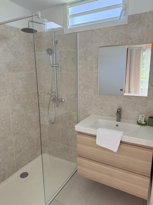 Salle de bains moderne à la Domaine de la Glacière avec douche pluie, meuble vasque suspendu et puits de lumière à Petit Bourg