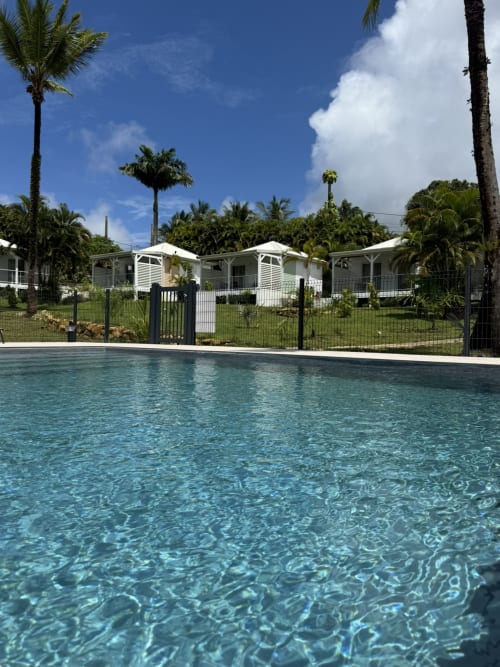 Piscine cristalline du Domaine de la Glacière à Petit-Bourg, Guadeloupe, avec chalets blancs et palmiers