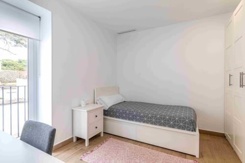 Bright bedroom at Residencia Demar in Godella with single bed, nightstand, and balcony access