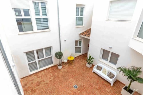 Courtyard at Residencia Demar hotel in Godella with terracotta brick patio, potted plants, and surrounding white buildings