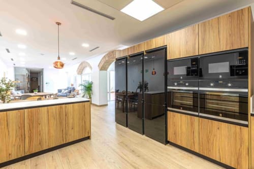 Cocina moderna del hotel Residencia Demar en Godella con muebles de madera, electrodomésticos negros y área de estar abierta