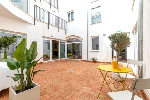 Residencia Demar courtyard in Godella with terracotta tiles, green plants, and yellow table