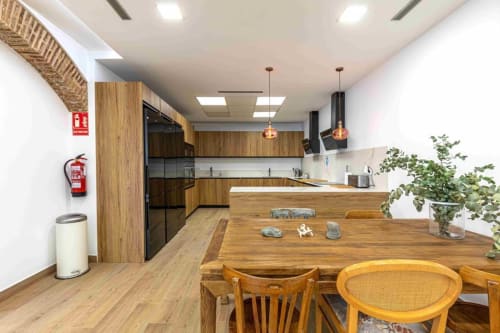 Cocina y comedor moderno en Residencia Demar en Godella con muebles de madera, luces colgantes y mesa de comedor