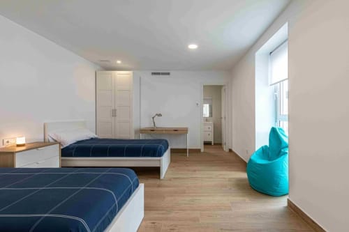Modern shared dormitory room at Residencia Demar in Godella with two beds, wardrobe, desk, and turquoise bean bag