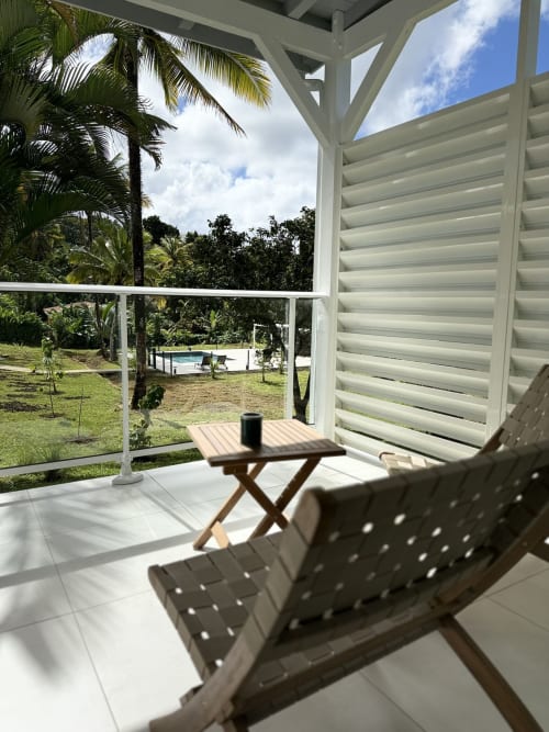 Véranda couverte du Domaine de la Glacière avec chaises longues, table en bois et vue sur jardin tropical à Petit Bourg