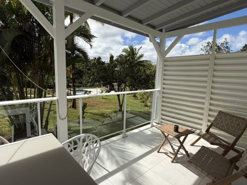 Patio avec moustiquaire à la Domaine de la Glacière à Petit Bourg, fauteuils de détente avec vue sur jardin tropical et piscine