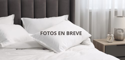 Habitación doble Residencia Demar en Godella con almohadas blancas, cabecero gris, mesita de noche y reloj despertador