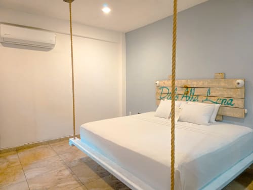 Dormitorio moderno del Hotel 40 Cañones en Mahahual con cama suspendida por cuerdas, ropa de cama blanca y decoración costera