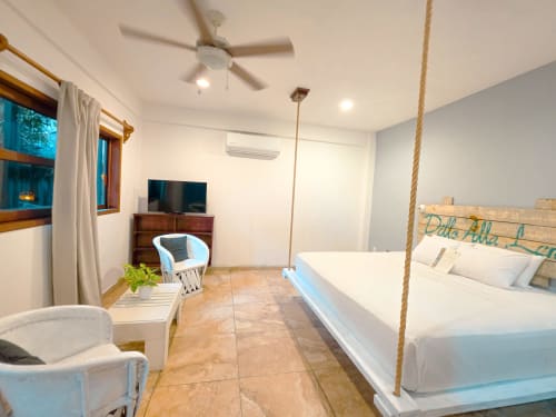 Habitación espaciosa del hotel 40 Cañones en Mahahual con cama columpio de cuerda, TV, aire acondicionado y comodidades modernas