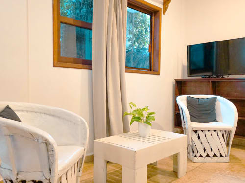 Moderna sala de estar en el Hotel 40 Cañones de Mahahual con sillas de mimbre blanco, mesita y vistas al trópico