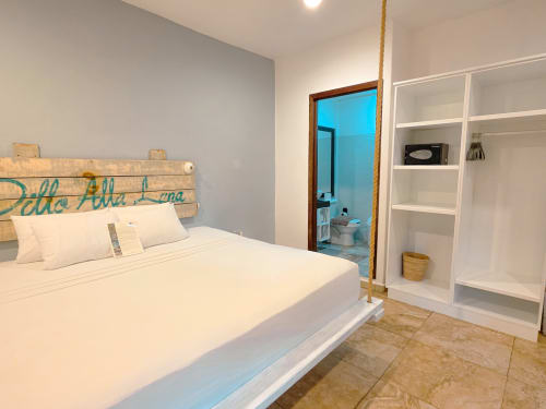 Habitación moderna del Hotel 40 Cañones en Mahahual con cama blanca, cabecera de madera y estantería blanca.