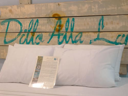 Almohadas blancas en cama con letrero de cabecero turquesa 'Pura Atta Ley' en Hotel 40 Cañones de Mahahual