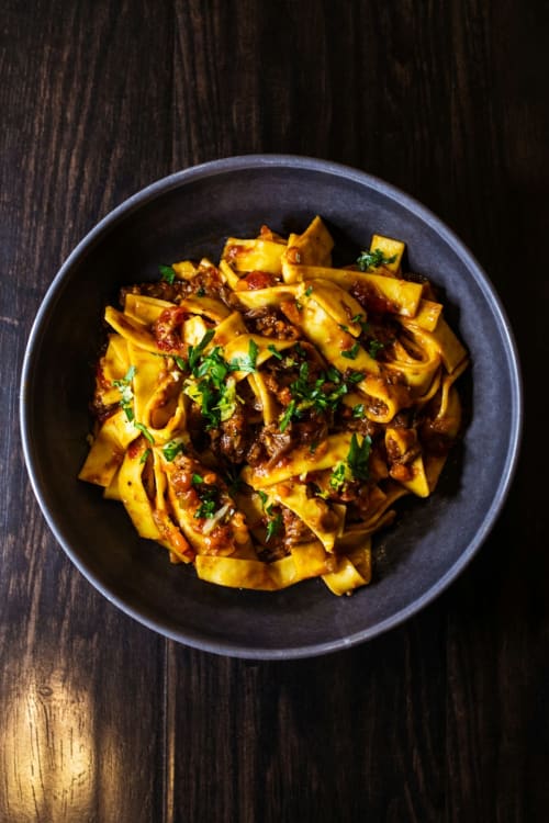 Pasta dorata al ragù in ciotola scura, guarnita di prezzemolo fresco, presso La Tour B&B, Oyace