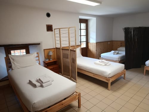 Camera dormitorio presso La Tour B&B a Oyace con letti in legno, biancheria bianca e divisori in legno