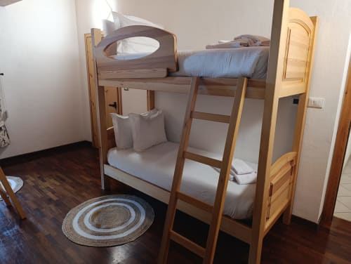 Camera quadrupla Frederick della La Tour B&B di Oyace con letti a castello in legno, biancheria bianca e tappeto circolare su pavimento scuro.