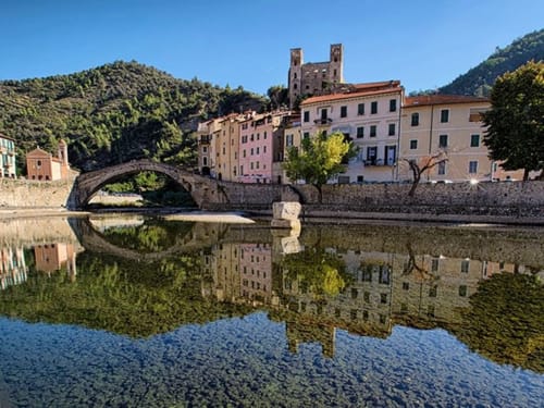 Villaggio medievale di Dolceacqua con ponte in pietra riflesso nel fiume, montagne e edifici storici, agriturismo Stecadò BnB