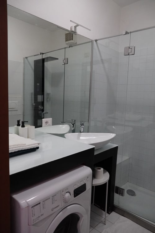 Modern bathroom in Carducci Apartment, THE V Collection, Turate with dual vessel sinks, glass shower enclosure, and washing