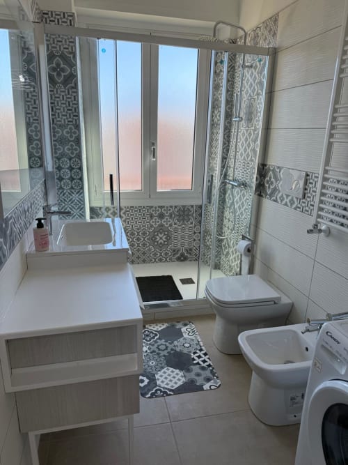 Bagno moderno di appartamento romano con doccia, toilette, bidet, lavabo, piastrelle decorative e vista sulla città