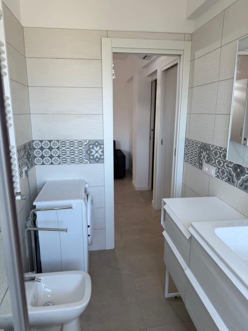 Bagno moderno in appartamento a Roma con piastrelle bianche, bordura decorativa, wc, bidet e portasciugamani