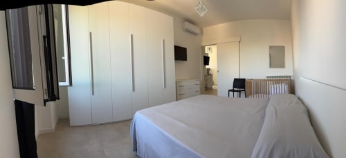 Camera da letto moderna in appartamento romano con armadio bianco, letto matrimoniale, lettino e arredamento minimalista
