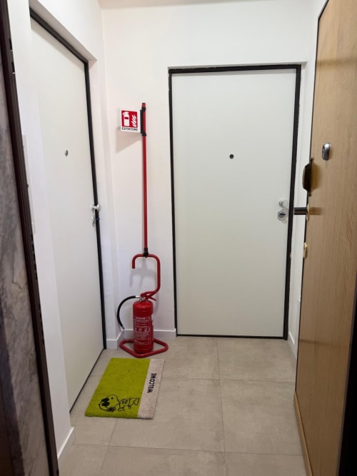 Ingresso di un edificio con zerbino di benvenuto, estintore rosso e più porte presso Home in Roma, Roma.