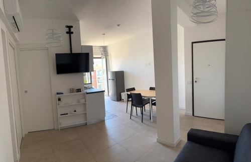 Moderno spazio abitativo a Roma con cucina aperta, zona pranzo, televisore e arredi minimalisti