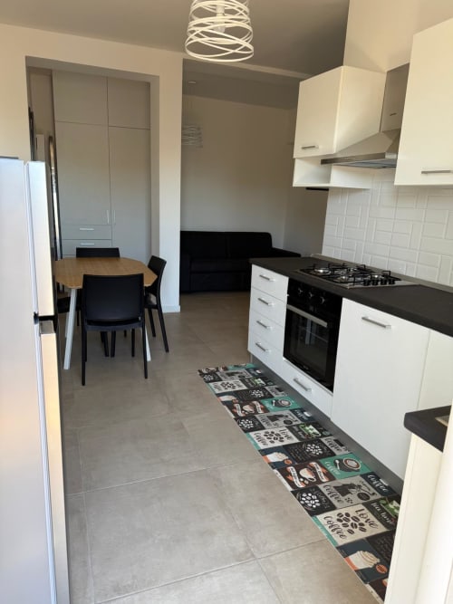 Cucina moderna con mobili bianchi, piano cottura a gas nero e zona pranzo in appartamento a Roma