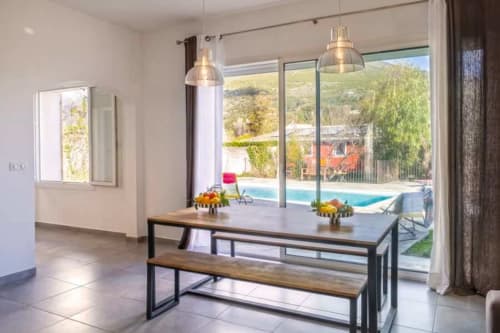 Salle à manger de la Villa Odette avec vue sur la piscine et le jardin à Centuri, Corse