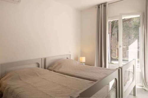 Chambre lumineuse avec lits jumeaux, portes-fenêtres sur jardin et lumière naturelle à la Villa Odette, Centuri