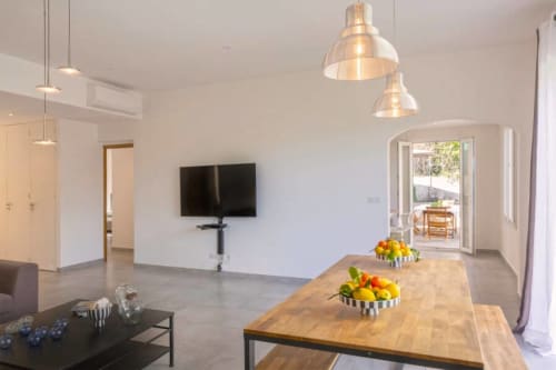 Villa moderne avec salle à manger, table en bois, luminaires suspendus, téléviseur écran plat et vue sur la terrasse à Centuri, Corse