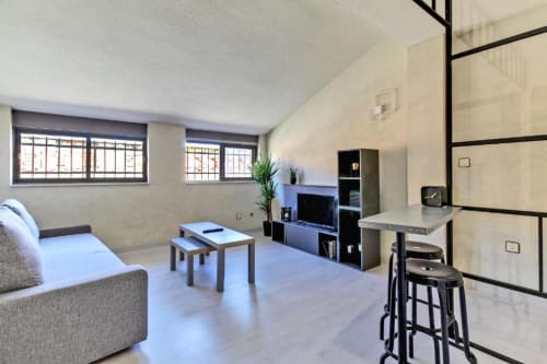 Habitación moderna del hotel MoneoHeritage Salamanca con sofá, televisor, kitchenette y zona de bar