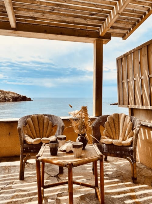 Terrasse en bord de mer à La Conciergerie du Cap Corse avec chaises tressées, pergola en bois et vue sur la Méditerranée à Centuri,