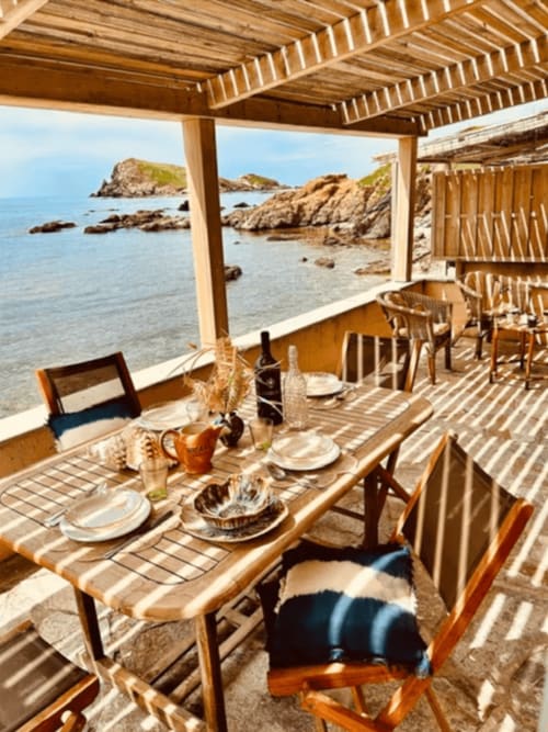 Terrasse en bois avec salle à manger à Villa Casapalmea, vue mer, côte rocheuse et îles à Centuri, Corse