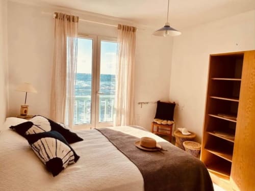 Chambre lumineuse avec balcon vue mer, étagères en bois et décoration côtière à Villa Casapalmea, Centuri