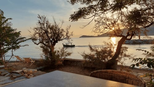 Vue sur la mer au coucher du soleil depuis la terrasse de la villa Domaine Robinson à Centuri, Corse, avec bateaux et paysage côtier