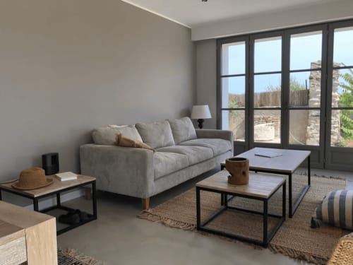 Salon moderne avec canapé gris et vue mer à la villa La Conciergerie du Cap Corse à Centuri, Corse