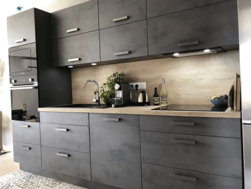Cuisine contemporaine gris foncé avec crédence en béton, électroménagers en acier inoxydable et plan de travail blanc à la villa Centuri